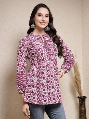 Woman wearing pink printed kurti with long sleeves and front pleats, styled with earrings and jeans